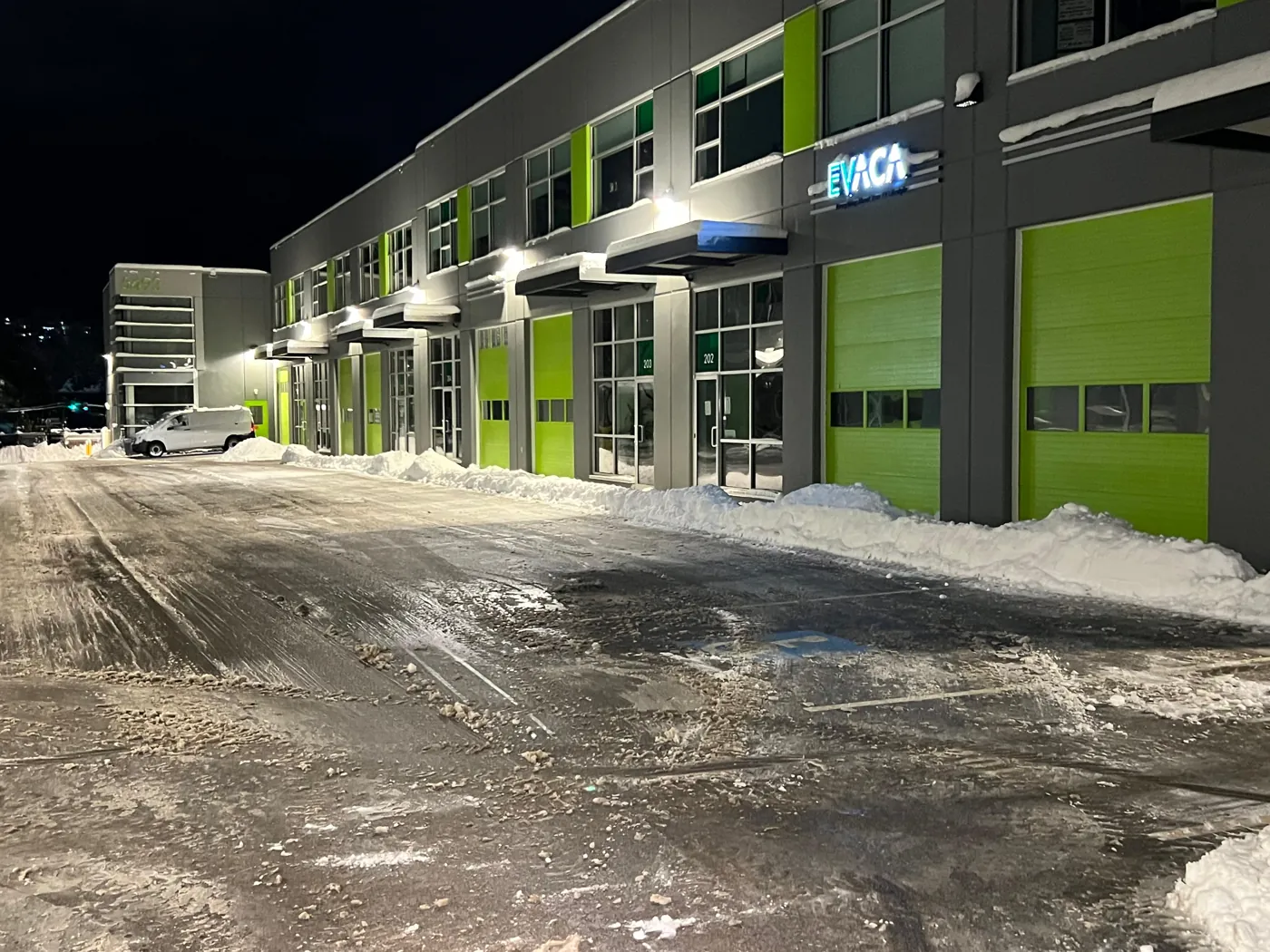 Commercial unit entrances and loading bays with snow gathered along the building edge